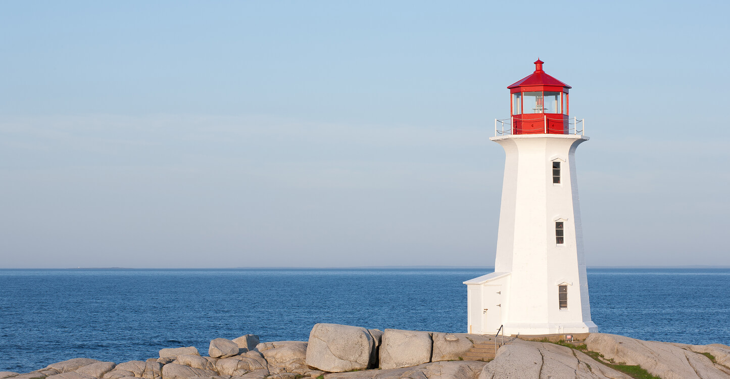 A photograph of a red and white lighthouse on the shore