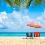 Two chairs underneath an umbrella on the beach