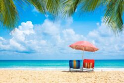 Two chairs underneath an umbrella on the beach