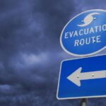 A photograph of a hurricane evacuation route sign with storm clouds in the background
