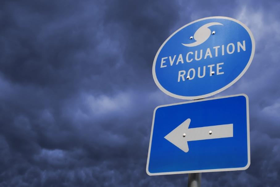 A photograph of a hurricane evacuation route sign with storm clouds in the background