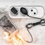 A photograph of a flaming cell phone plugged into an electrical socket