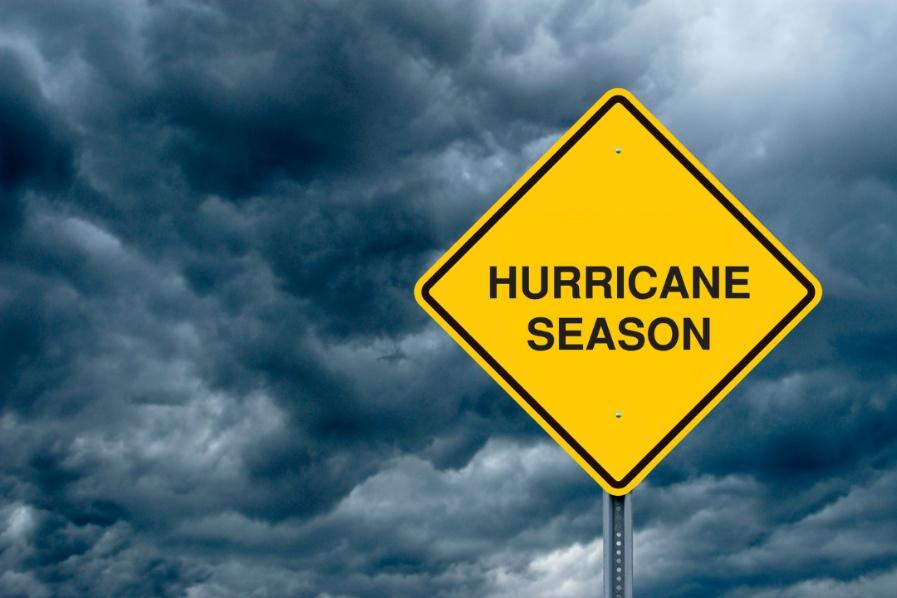 A photograph of a hazard sign that reads "Hurricane Season" with storm clouds in the background.